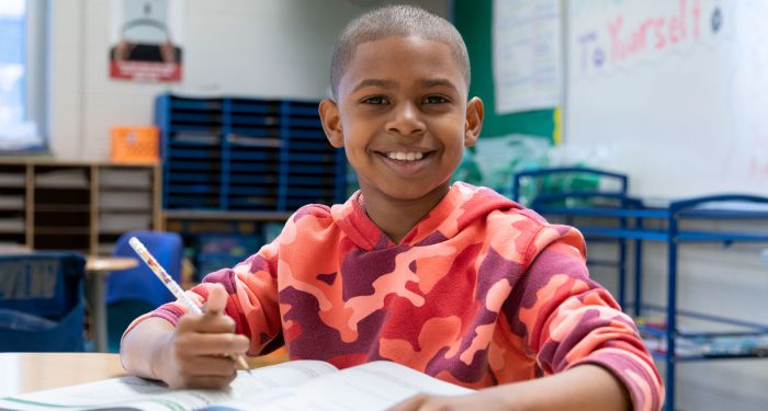 A child in a classroom smiling.