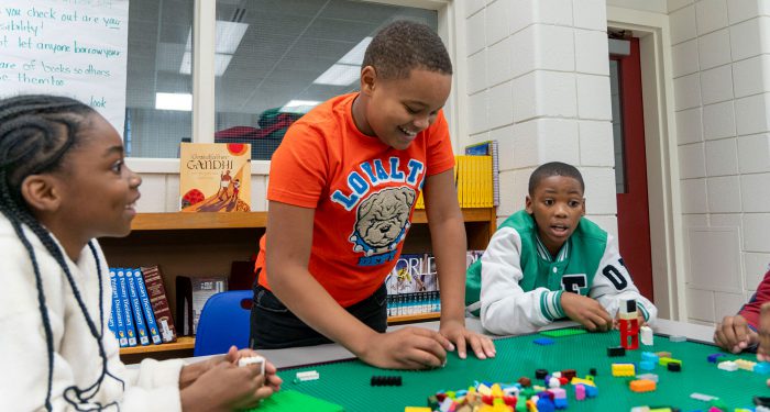Children at a large Lego table building with Lego.