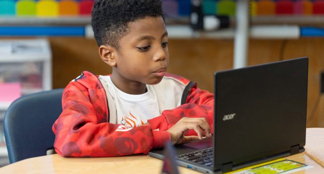 A boy concentrates as he uses a computer.