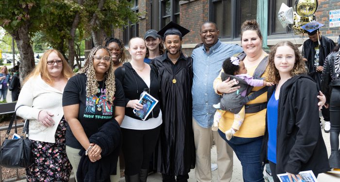 A graduate outside with their family.