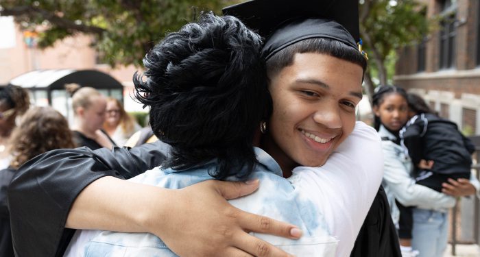 A graduate hugging a woman.