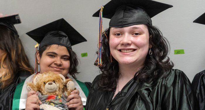 Two graduates in black cap and gowns.