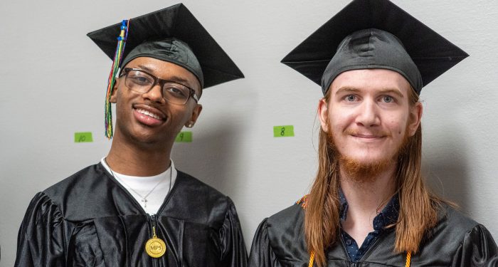 Two graduates in black cap and gowns.