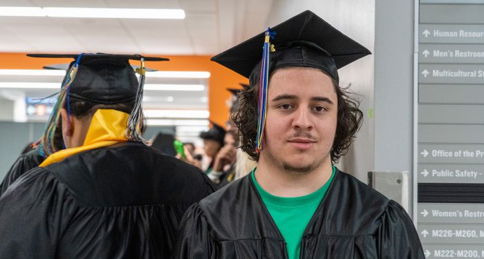 Two graduates in black cap and gowns.