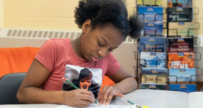 A child at a table working on an assignment.