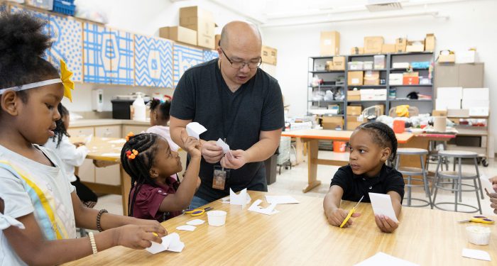 A teacher helps his young students with a project.