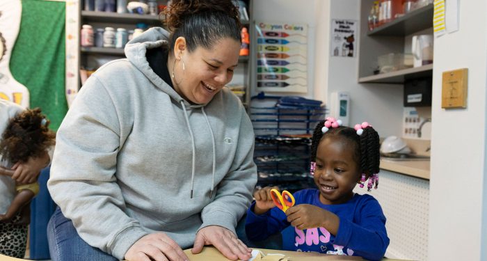 A teacher and her young student smiling.