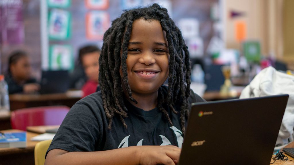 A smiling student using a computer.