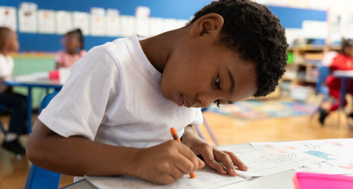 A young student in a classroom coloring.