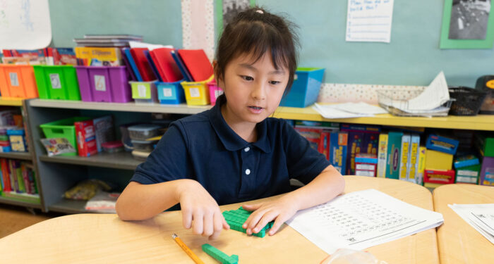 A young child in a classroom using counting blocks.