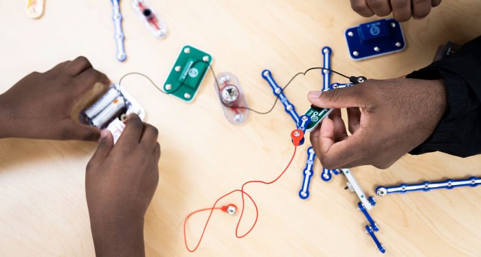 Overhead view of two hands assembling an electrical circuit unit.