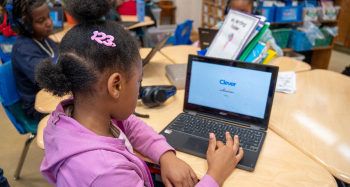 A child in a classroom uses a computer.