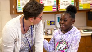 A child smiles at her teacher.