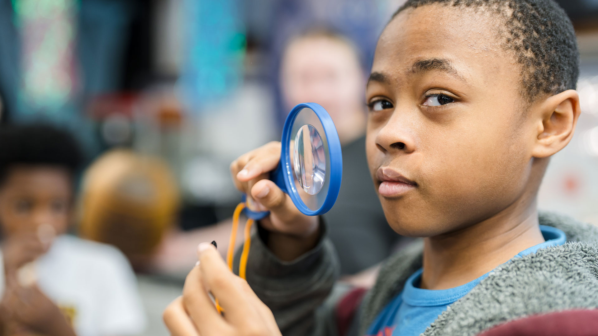 A boy looking through a magnifying glass.