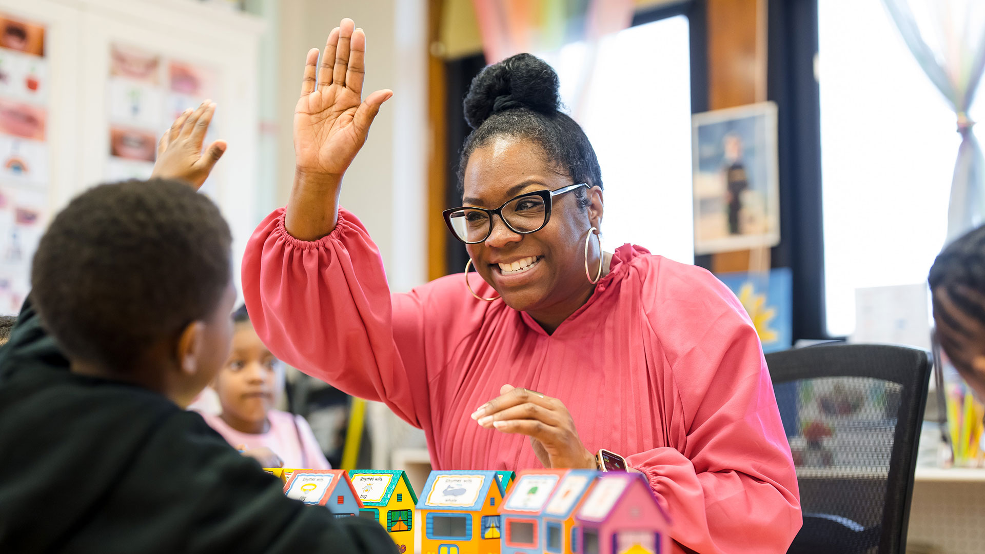 A teacher gives her young student a high five.