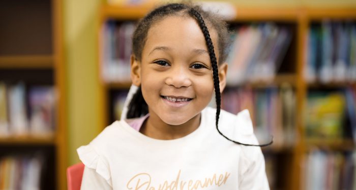 Close-up of a smiling girl with the word "Daydreamer" on her shirt.