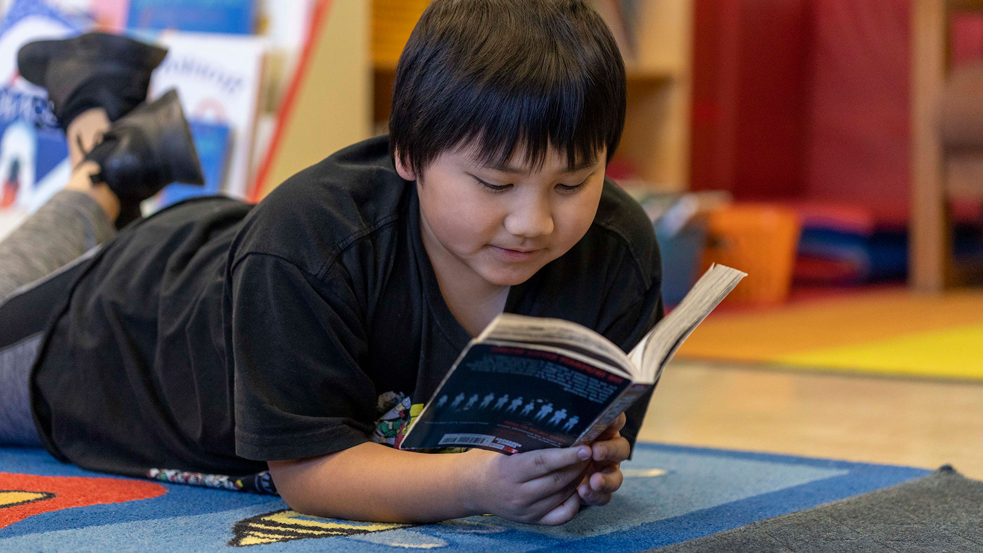 A boy lays on the floor, reading a book.