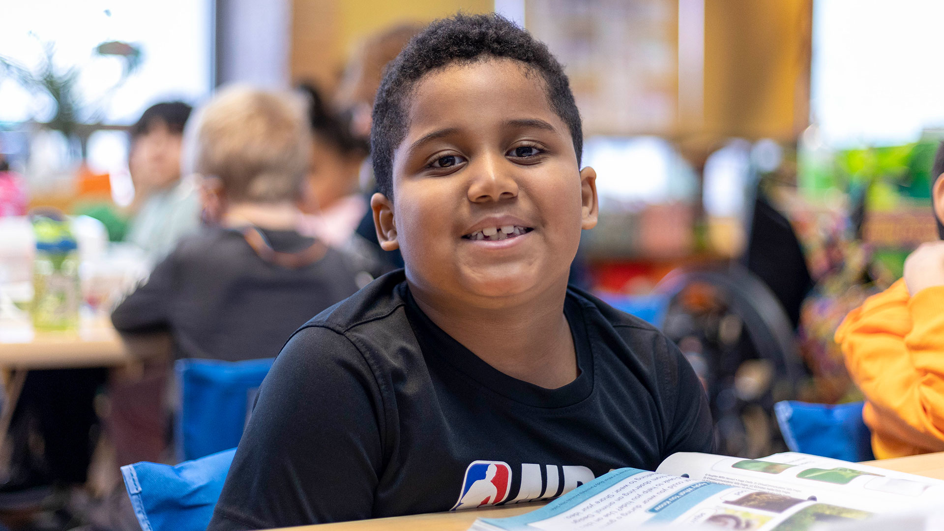 A smiling boy in a classroom.