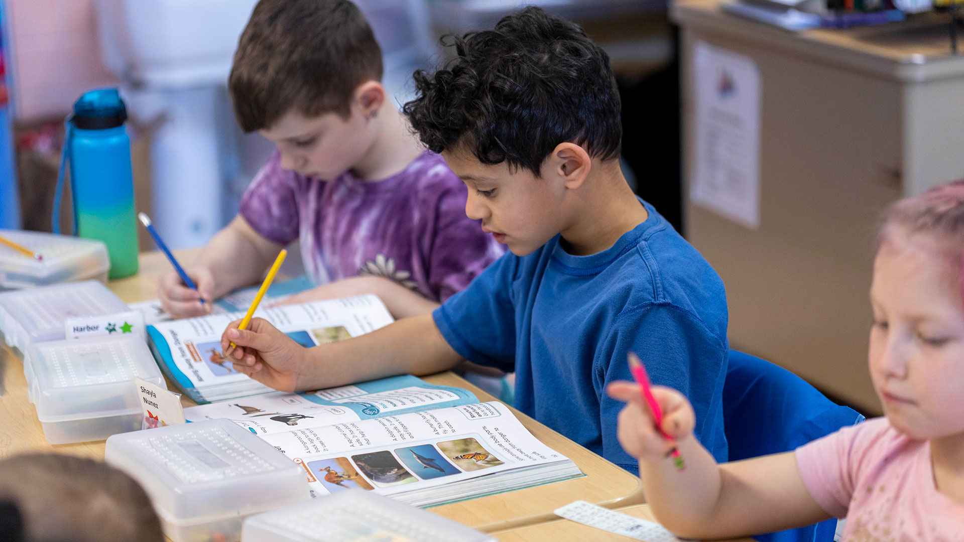 Young students looking at their workbooks.