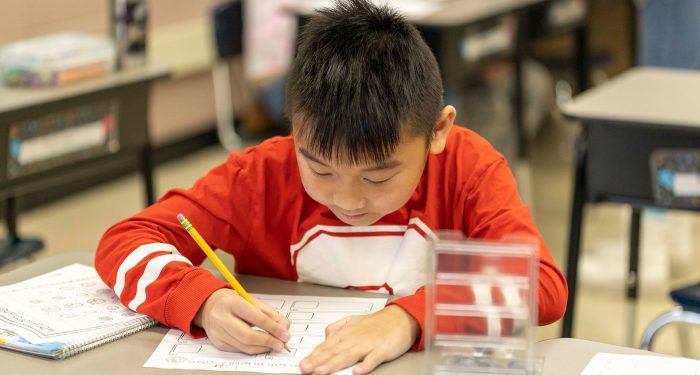 A boy at a table writing.