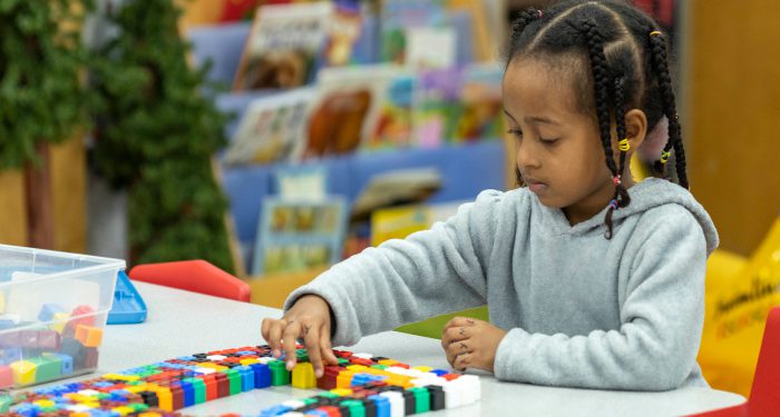 A young girl concentrates while working with blocks.