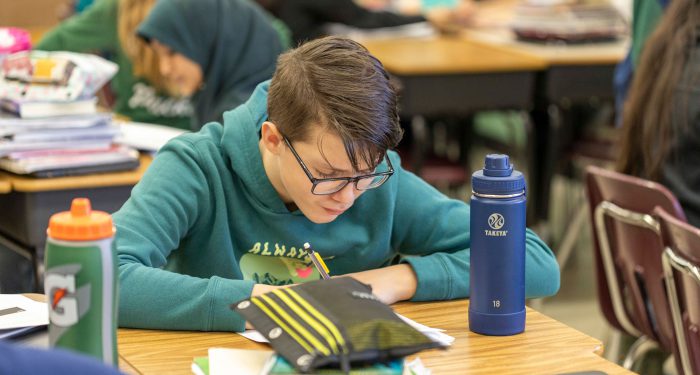 A student at his desk writing.