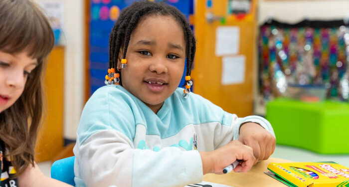 A young girl in a classroom coloring.