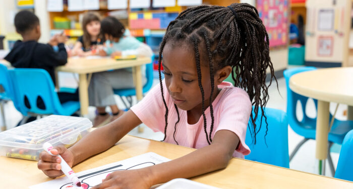 A young child in a classroom coloring.