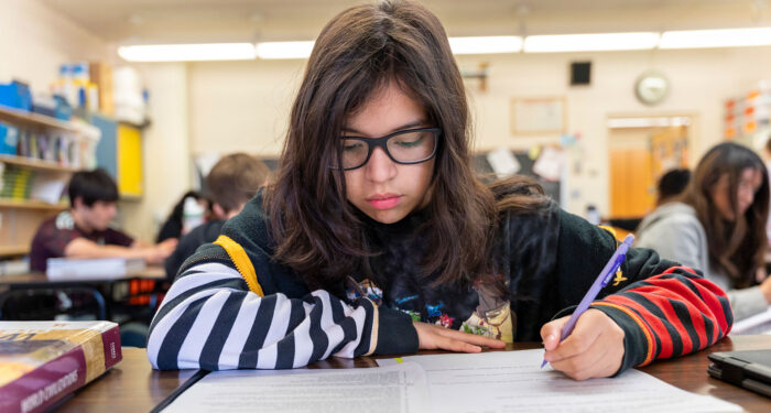 A student in a classroom writing.