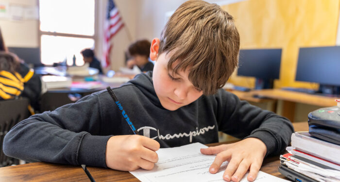 A student in a classroom writing.
