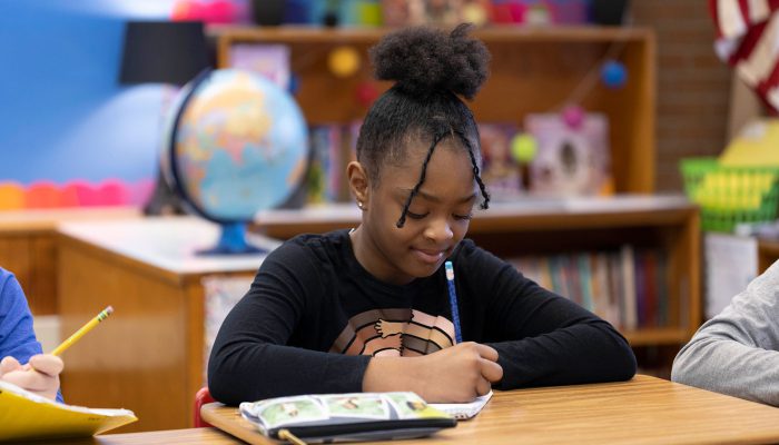 A girl in a library writing.