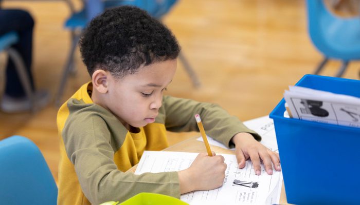 A young boy practices writing the letter 'y'