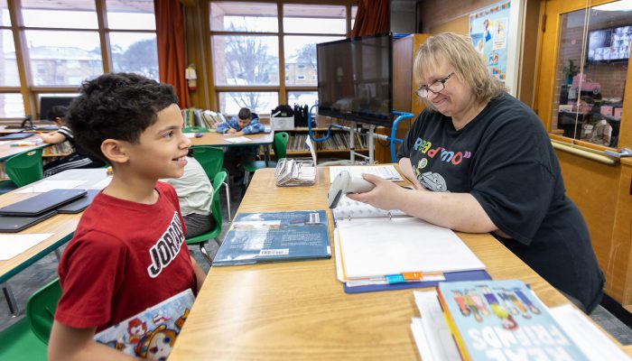 The librarian scans a book while a student smiles.