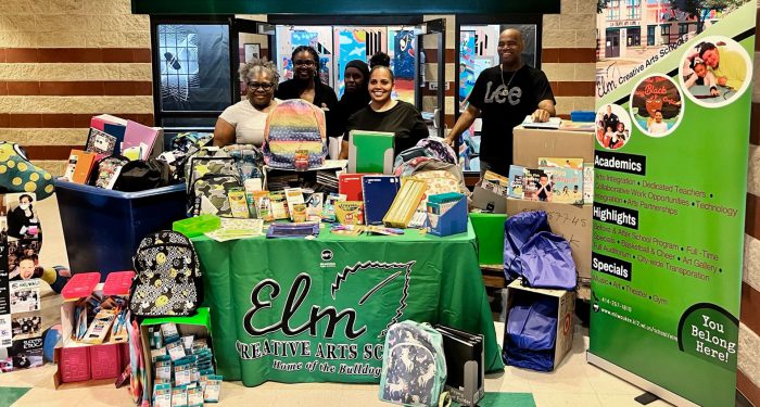 Teacher and staff with school supplies and backpacks.