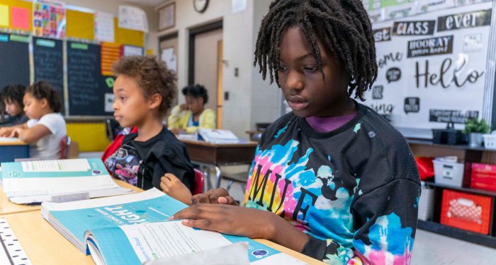 Students in a classroom looking at their workbooks.