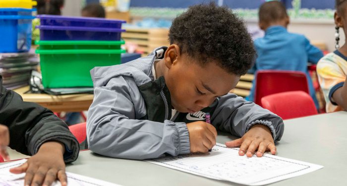 A young child at a table coloring.