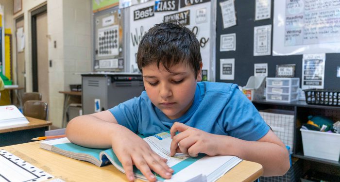 A student at a desk reading a book.