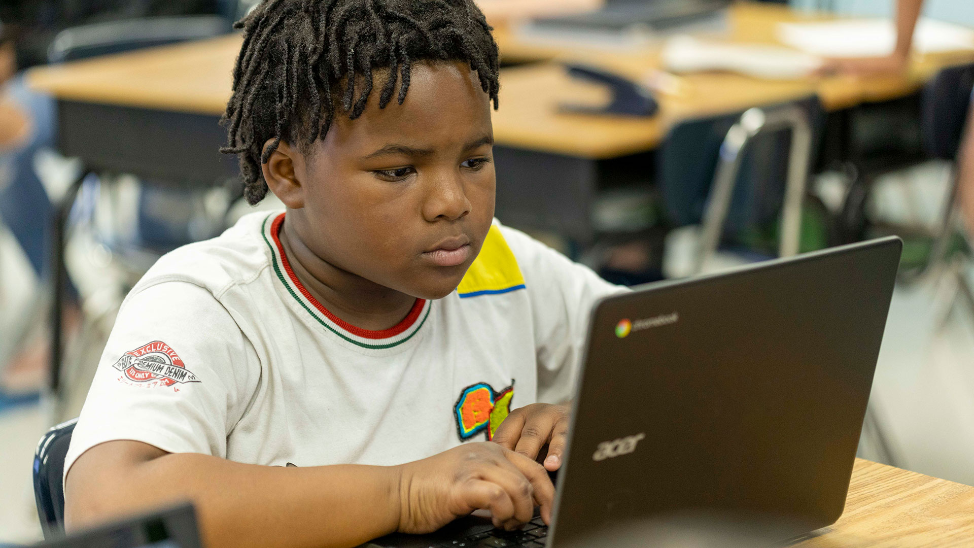 A boy concentrates as the types on his laptop.