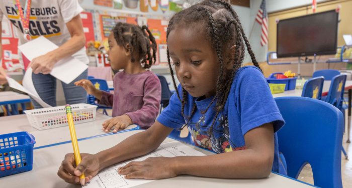 Young students at a table writing on worksheets.