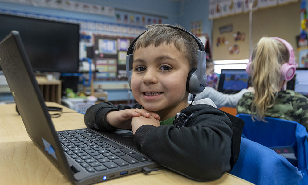 A young boy at a laptop with headphones on