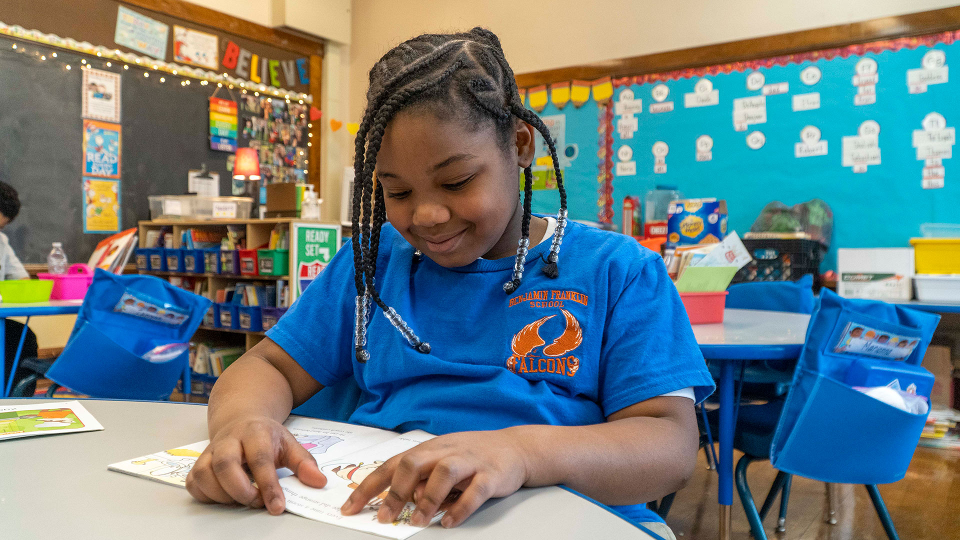 A girl sits at a table and looks at a book.