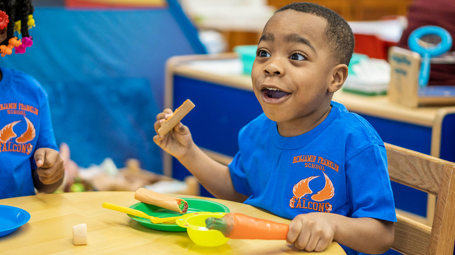 A smiling boy plays with pretend food.