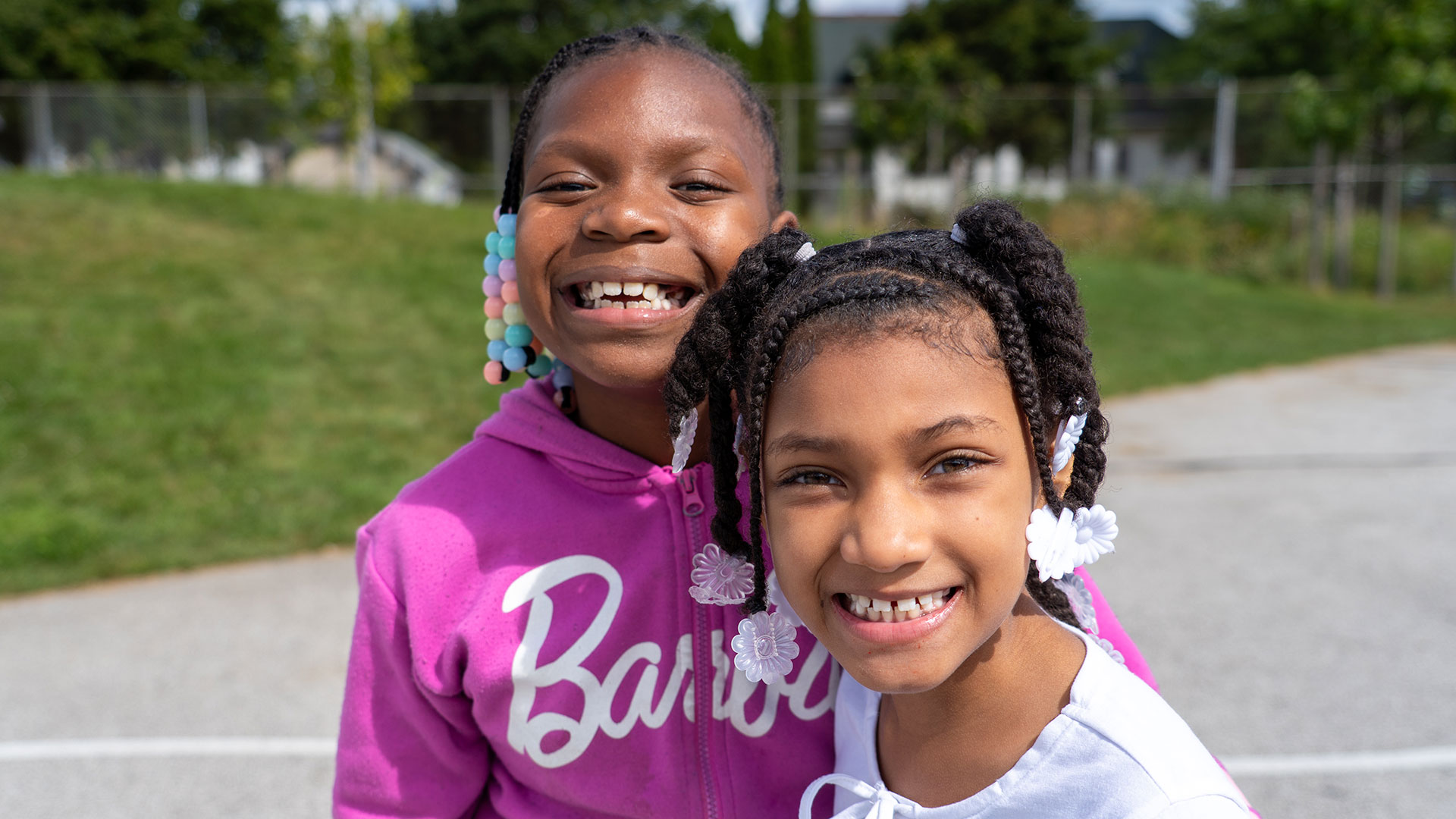 Two smiling girls outside.
