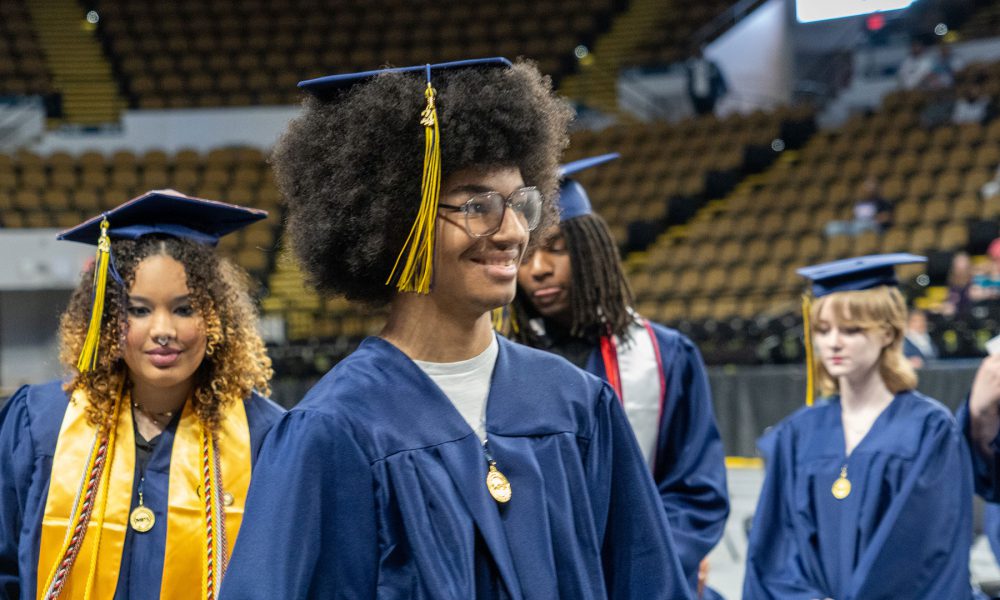 Graduates smiling as they enter the ceremony.