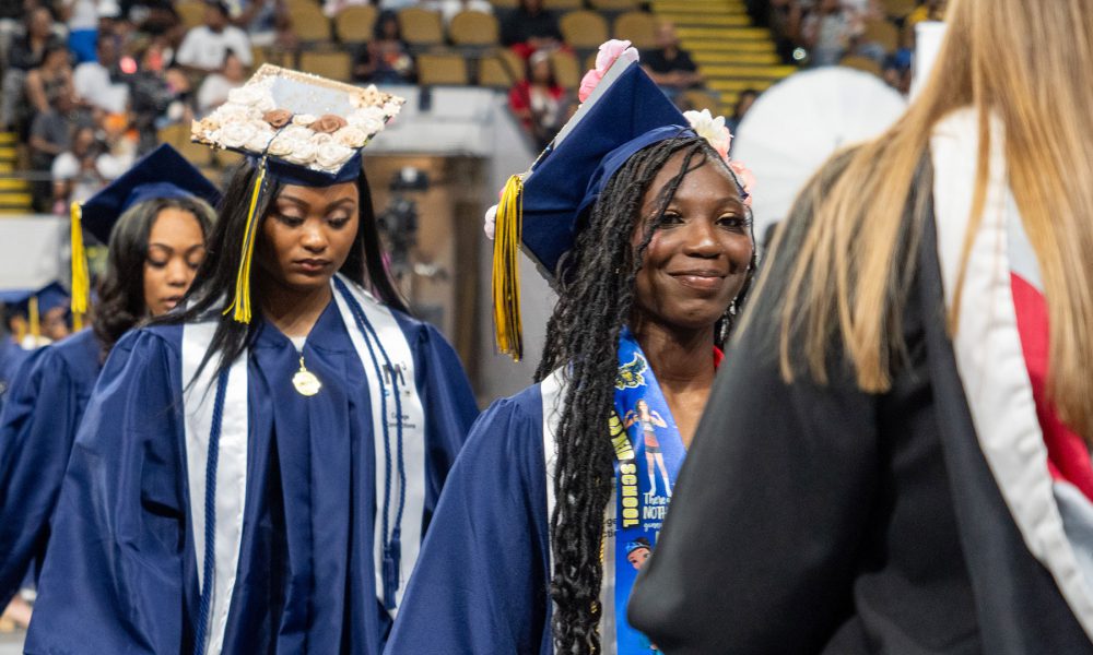 Graduates smiling as they enter the ceremony.
