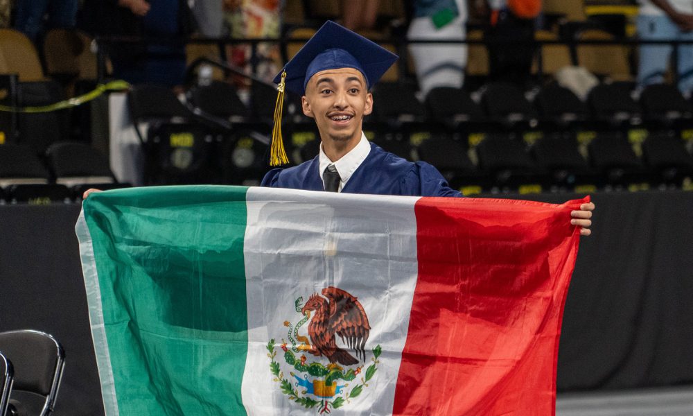 A student holds up a flag of Mexico.