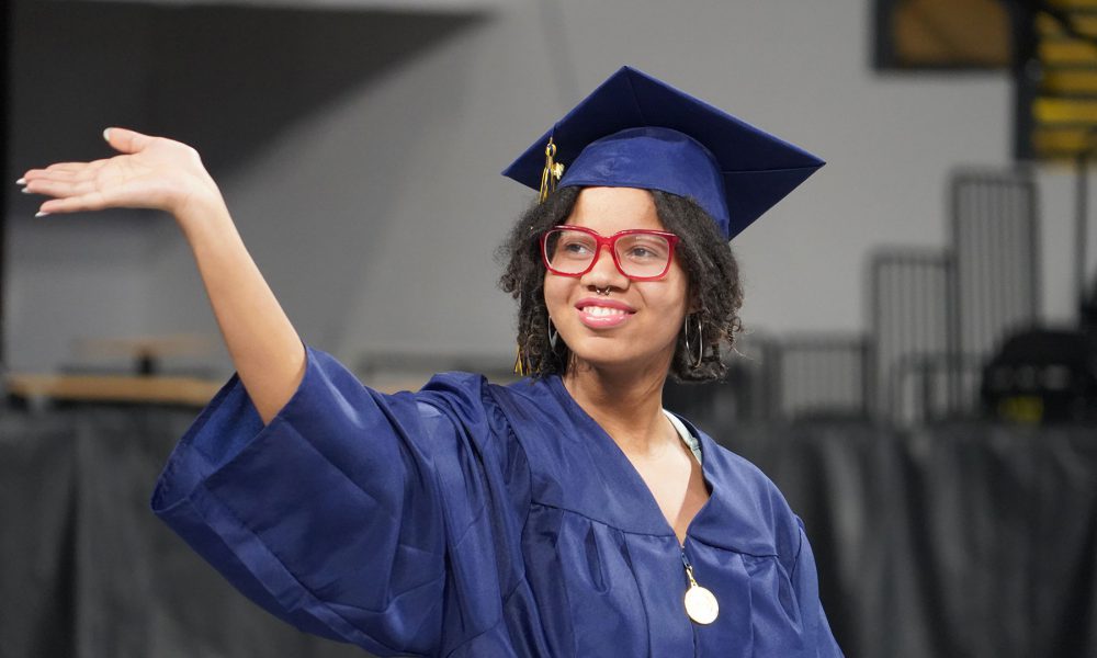 A graduate waves while entering the ceremony.