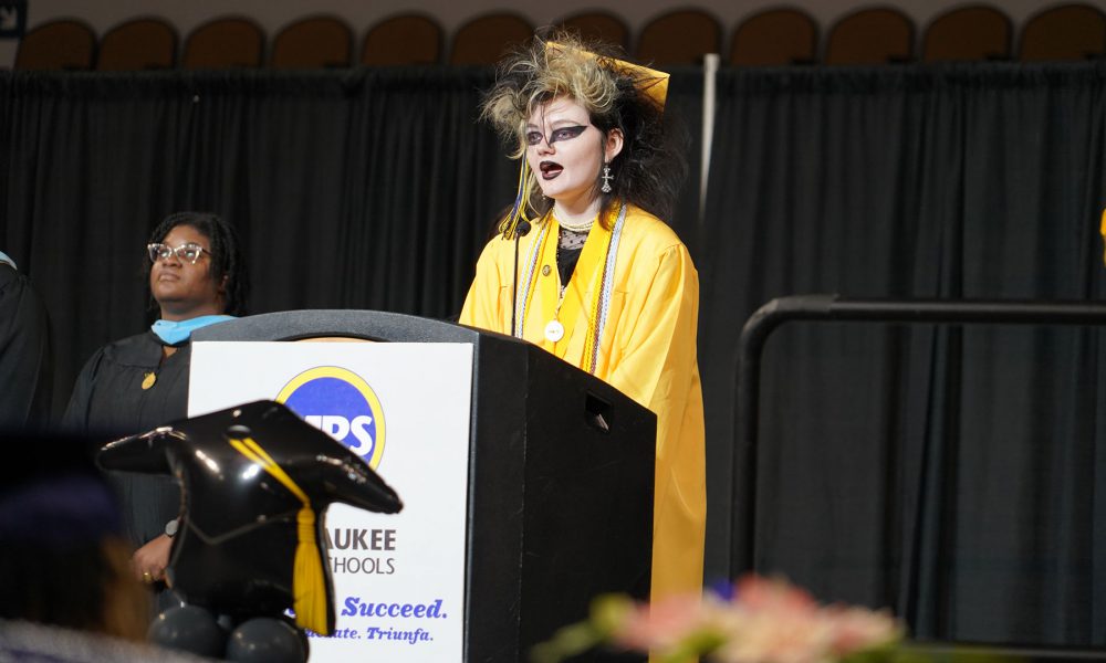 A graduate speaking at a podium.