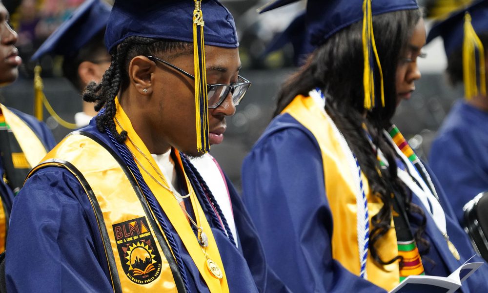 Close-up of graduates reading the program.