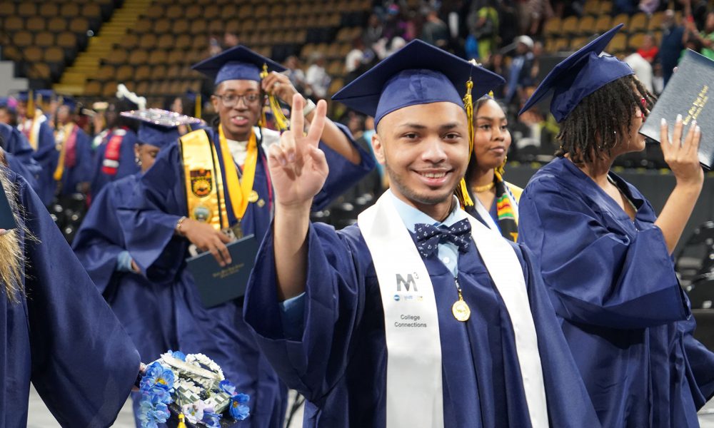 Graduates smiling as they leave the ceremony.